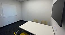 Teen Study Room A with table, four chairs, monitor and dry erase board on wall