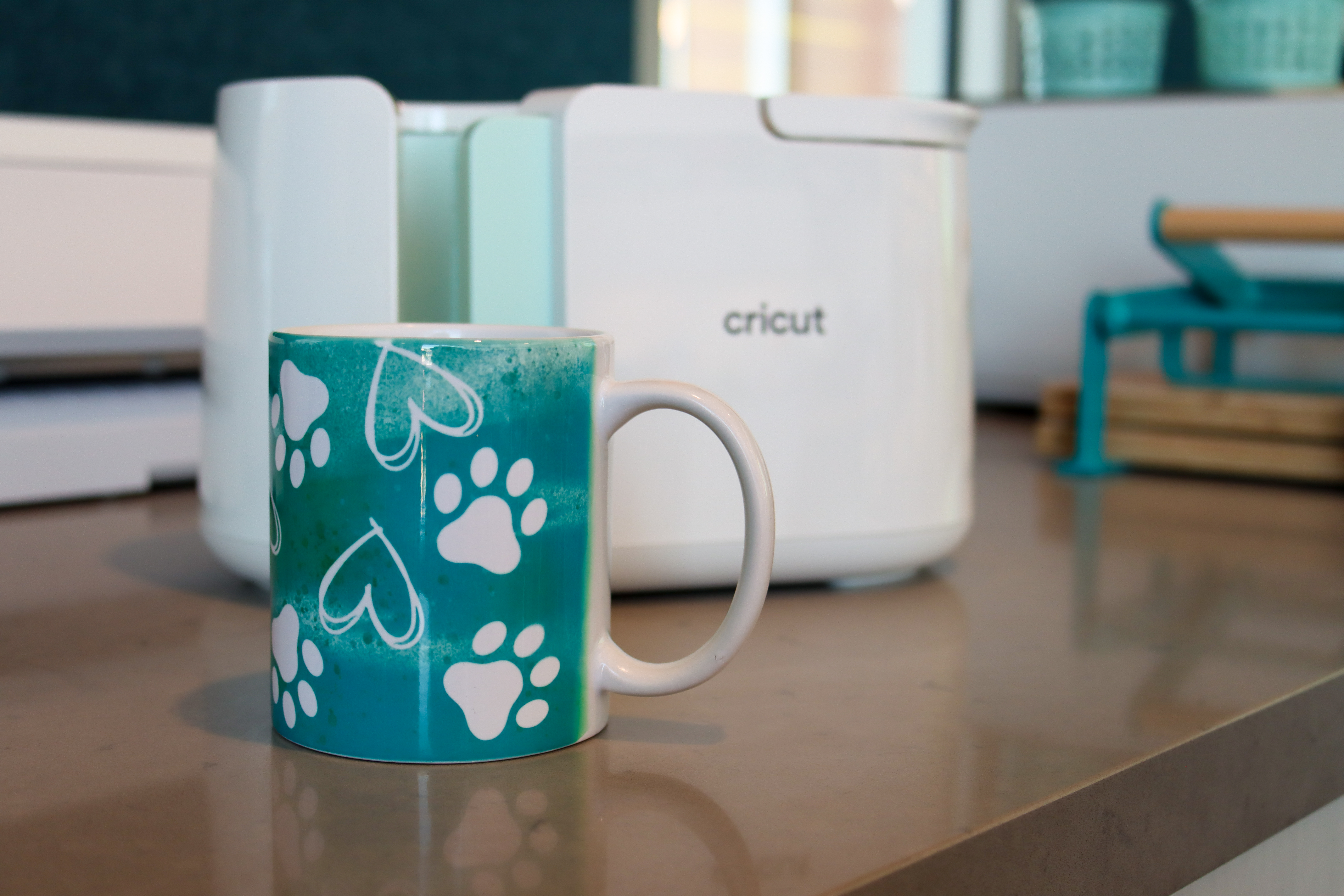 Coffee mug with a printed design of teal hearts and paw prints