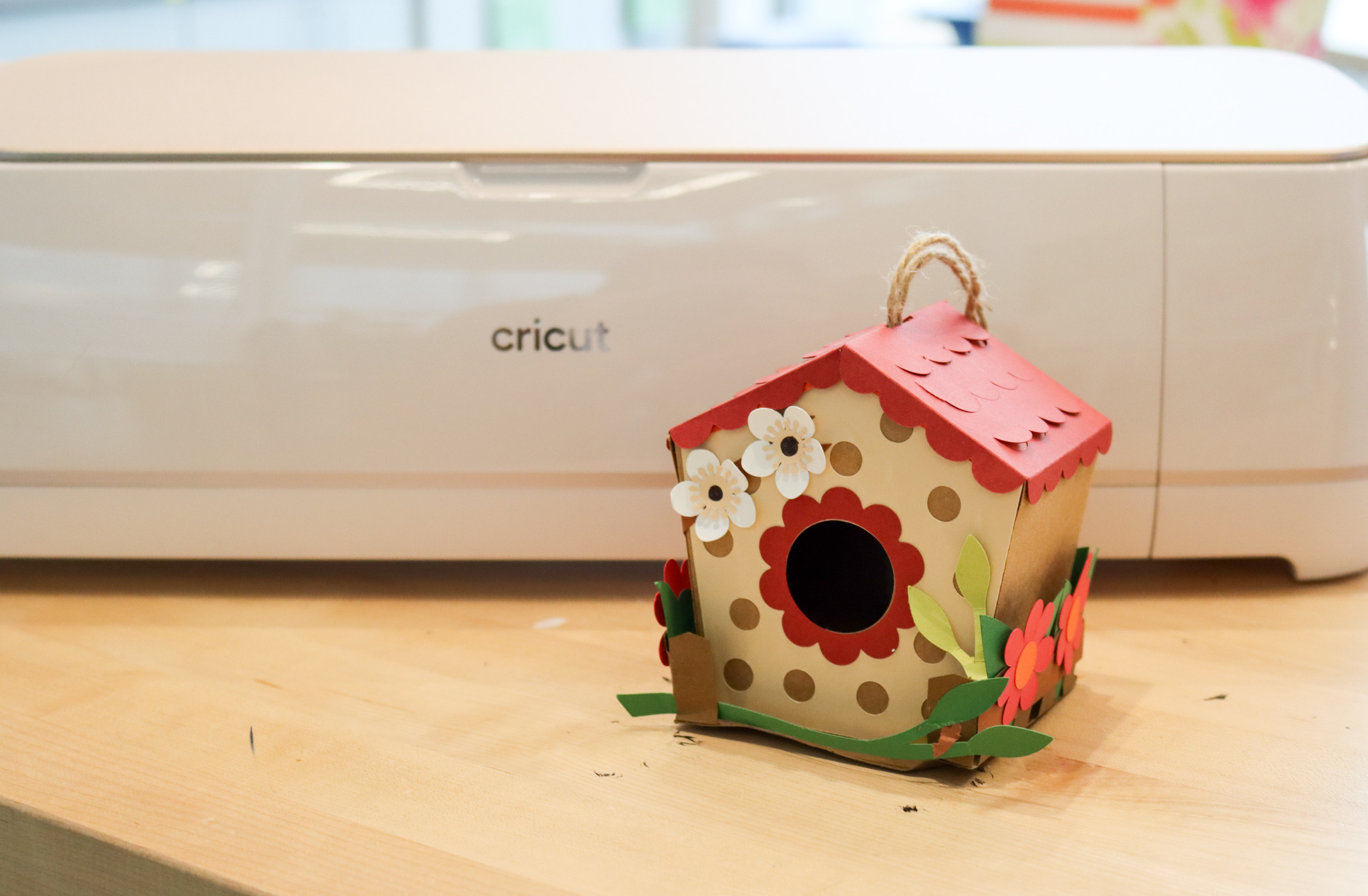 Small decorative birdhouse made with paper embellished with paper flowers