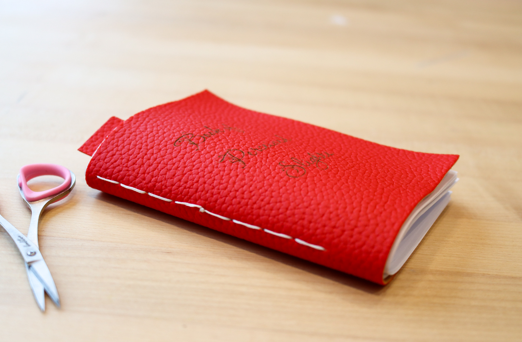 Red faux leather journal with white thread stitched binding