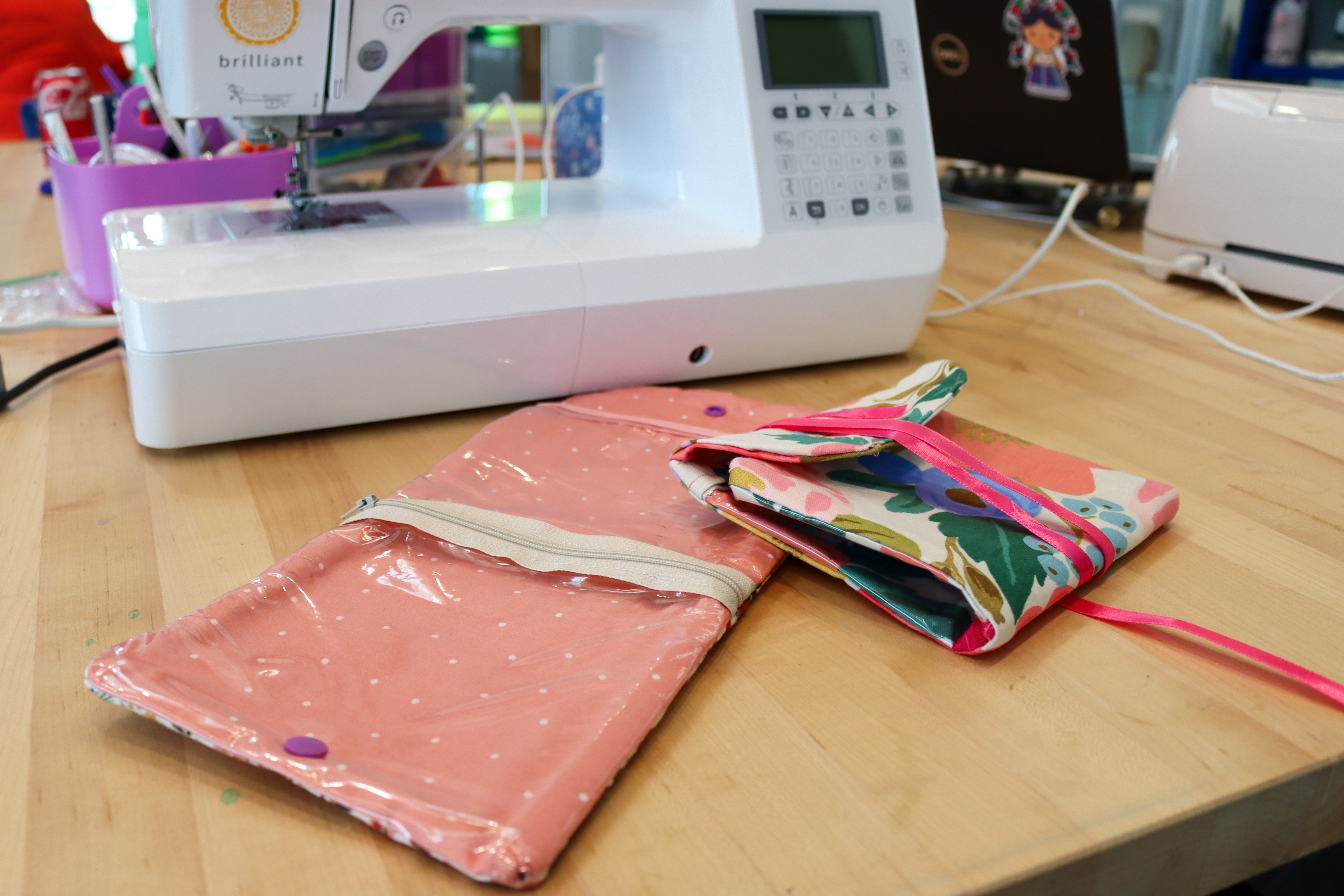 A tri-fold travel pouch with clear pockets made of floral print fabric.