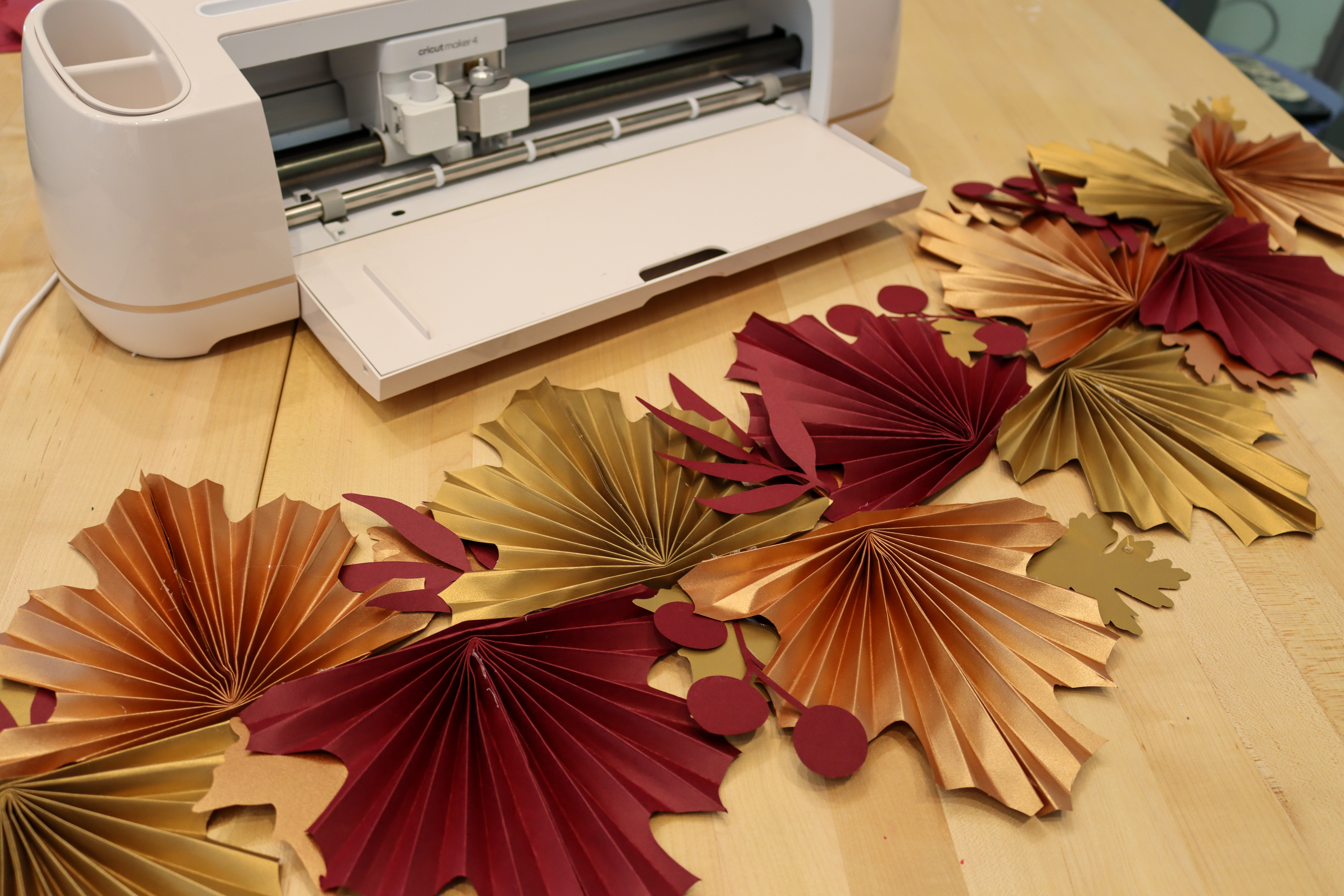 Table runner made out of paper leaves in shades of red and gold.