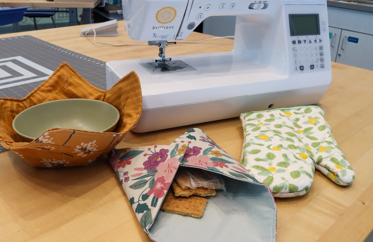 Sewn bowl cozy, snack bag, and oven mitt on a table in Studio 411.