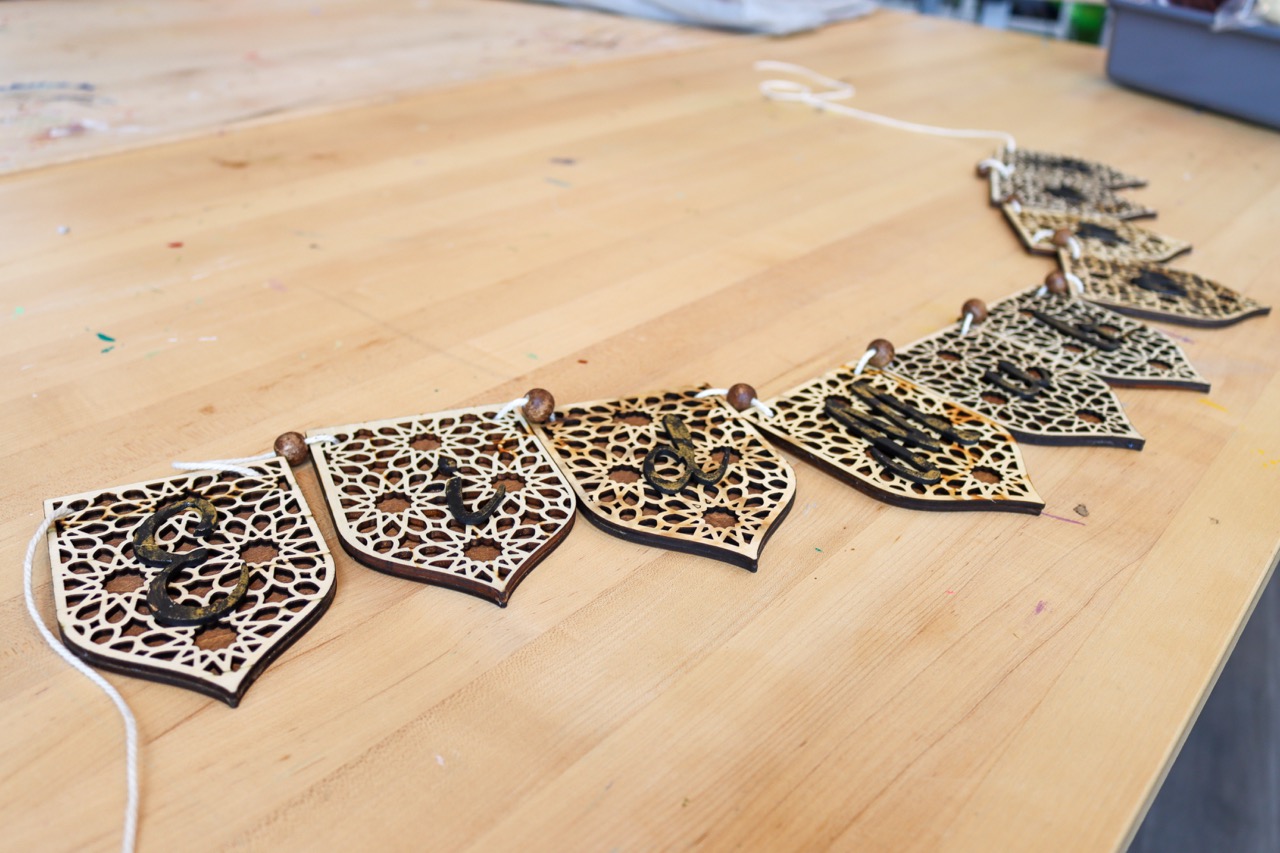 Wooden banner with individual letters on pennant-style wooden flags spelling out Eid Mubarak