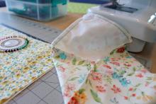 Close-up of a floral fabric sandwich wrap on a table next to a sewing machine