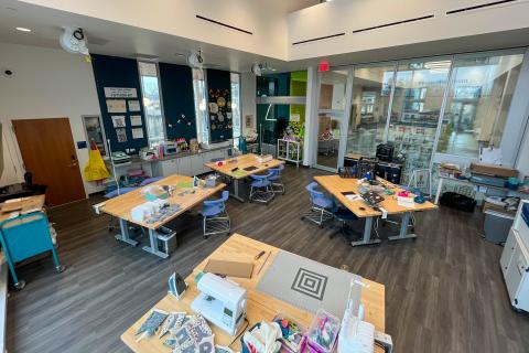 Studio 411 makerspace with four large crafting tables wit craft supplies on them.